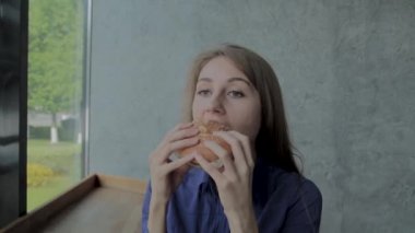 Güzel kız hamburger yiyor. Fast food restoran