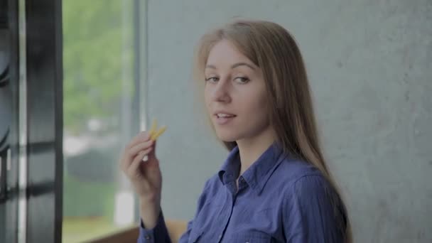 Hermosa chica sosteniendo papas fritas en un restaurante de comida rápida — Vídeo de stock