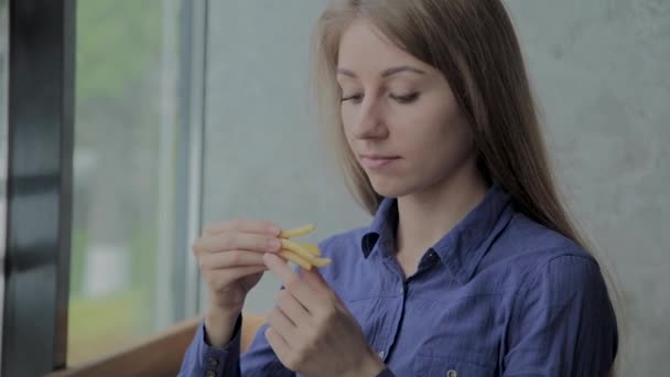 Hermosa chica sosteniendo papas fritas en un restaurante de comida rápida — Vídeos de Stock