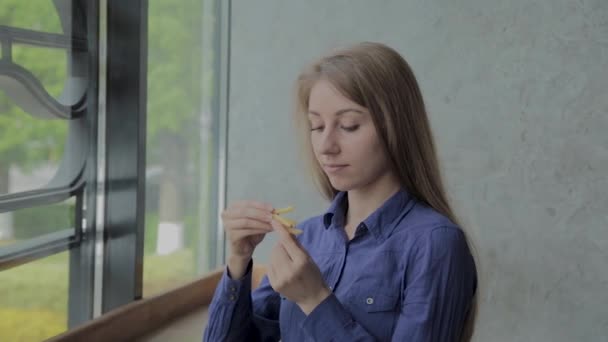 Красивая девушка держит жареный картофель в ресторане быстрого питания — стоковое видео