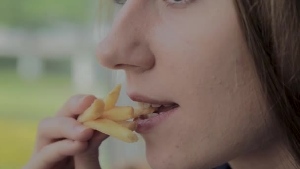 Hermosa chica sosteniendo papas fritas en un restaurante de comida rápida — Vídeos de Stock