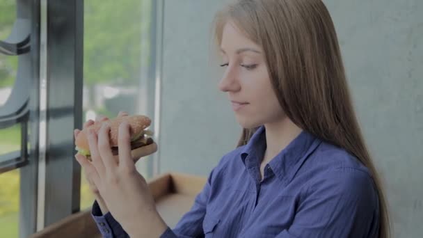 Belle fille tenant un hamburger dans ses mains. Restauration rapide . — Video