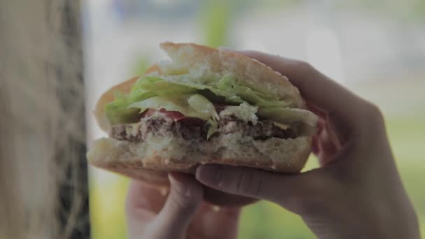 Hermosa chica come una hamburguesa. Restaurante de comida rápida — Vídeos de Stock