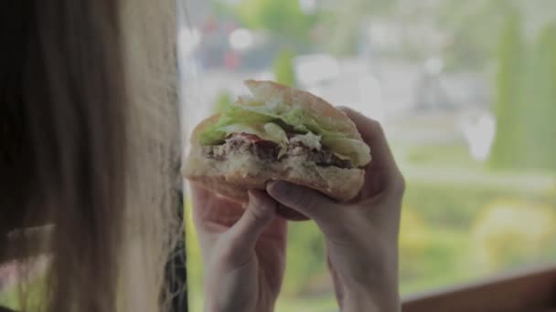 아름다운 소녀는 햄버거를 먹는다. 패스트푸드 레스토랑 — 비디오