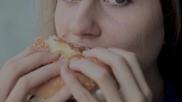 Красивая девушка ест бургер. Ресторан быстрого питания — стоковое видео