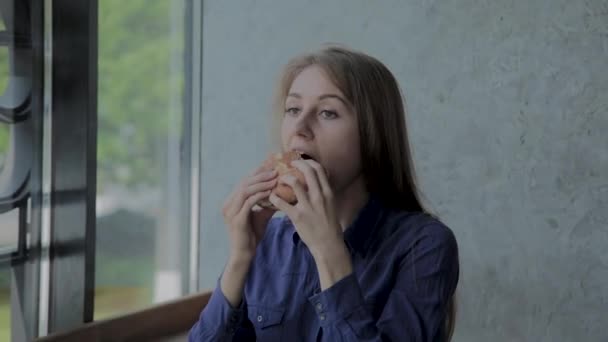 Mooi meisje eet een hamburger. Fast Food Restaurant — Stockvideo