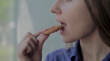 Kız soğan halkaları yiyor ve bir fast-food restoranda gülümsüyor.