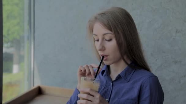 Hermosa chica bebe manzana fresca sentada junto a la ventana . — Vídeos de Stock