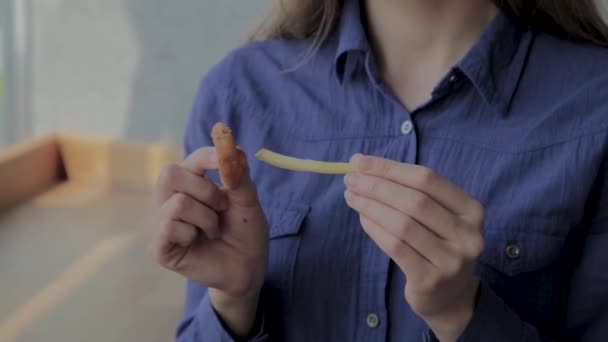 Chica inserta un pedazo de papas fritas en el anillo de cebolla . — Vídeos de Stock