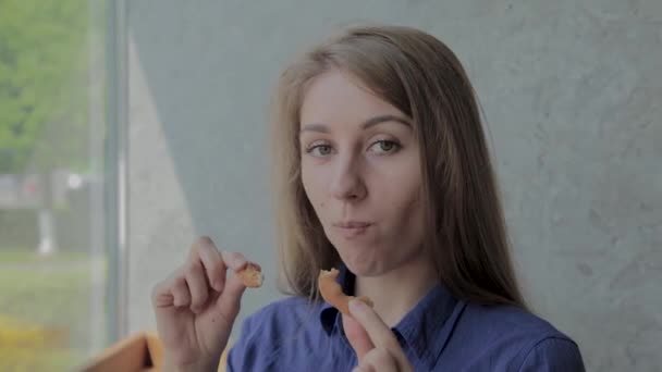 Menina come anéis de cebola e sorri em um restaurante fast food . — Vídeo de Stock