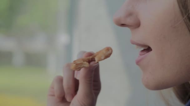 Дівчина їсть цибулю кільця і посміхається в ресторані швидкого харчування . — стокове відео