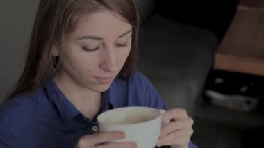 Güzel bir kız bir kafede oturuyor ve kahve içiyor.