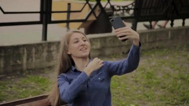 Güzel mutlu kız bir tezgah üzerinde parkta selfie yapma.