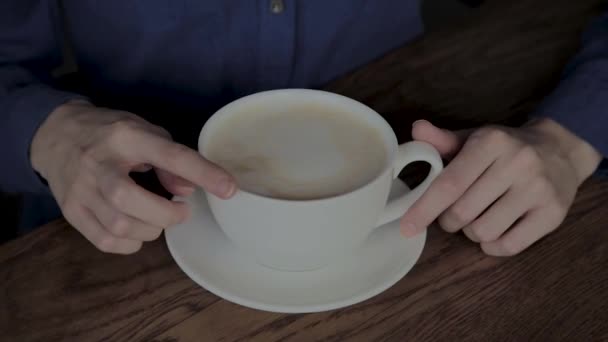 Mooi meisje zitten in een cafe met een kopje cappuccino. — Stockvideo