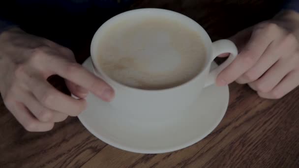 Vacker flicka som sitter i ett kafé med en kopp cappuccino. — Stockvideo