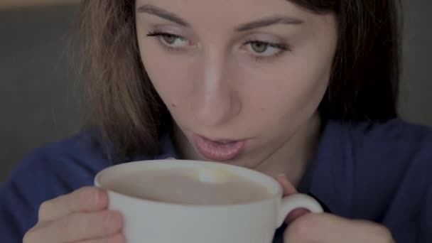 Красивая девушка сидит в кафе и пьет кофе . — стоковое видео