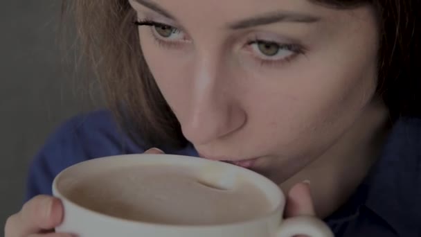 Een mooi meisje zit in een cafe en het drinken van koffie. — Stockvideo