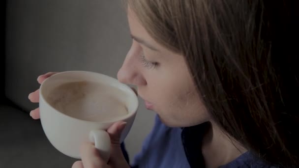 Une belle fille est assise dans un café et boit du café . — Video