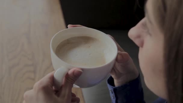 Una bella ragazza è seduta in un caffè e beve caffè . — Video Stock