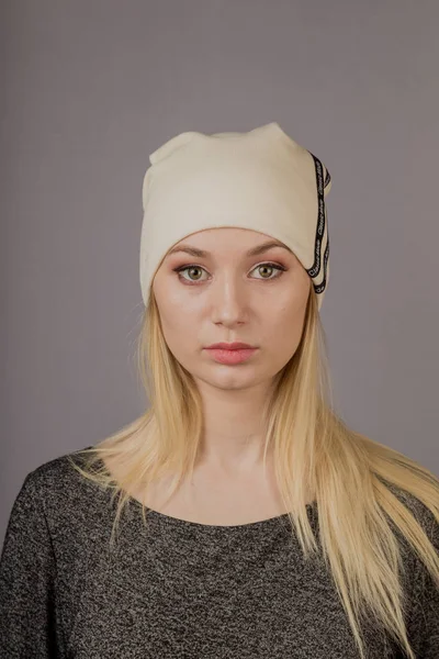 Portrait of a beautiful young girl in a stylish headdress with natural makeup on a gray background. — Stock Photo, Image