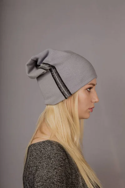 Retrato de una hermosa joven en un elegante tocado con maquillaje natural sobre un fondo gris . — Foto de Stock