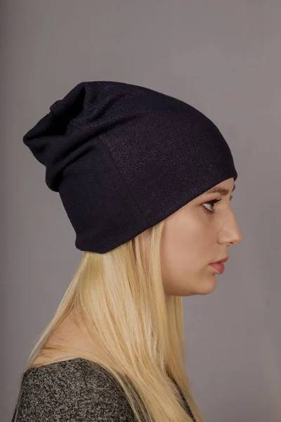 Retrato de una hermosa joven en un elegante tocado con maquillaje natural sobre un fondo gris . — Foto de Stock