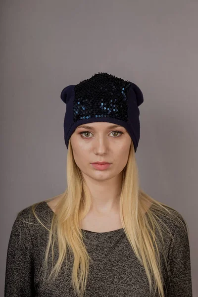 Portrait of a beautiful young girl in a stylish headdress with natural makeup on a gray background. — Stock Photo, Image