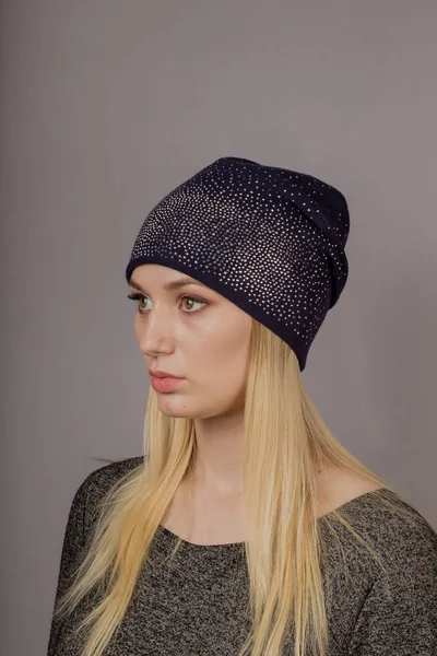 Retrato de una hermosa joven en un elegante tocado con maquillaje natural sobre un fondo gris . — Foto de Stock