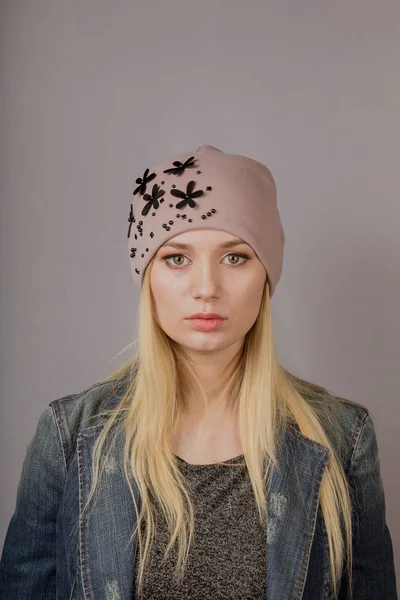 Retrato de una hermosa joven en un elegante tocado con maquillaje natural sobre un fondo gris . — Foto de Stock