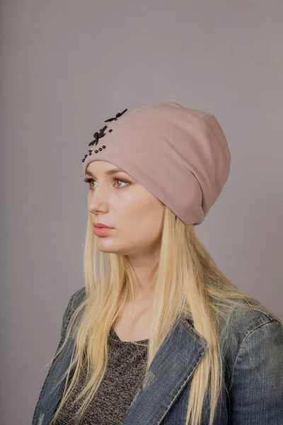 Retrato de una hermosa joven en un elegante tocado con maquillaje natural sobre un fondo gris . —  Fotos de Stock