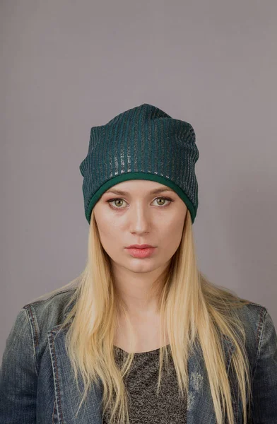 Retrato de una hermosa joven en un elegante tocado con maquillaje natural sobre un fondo gris . — Foto de Stock