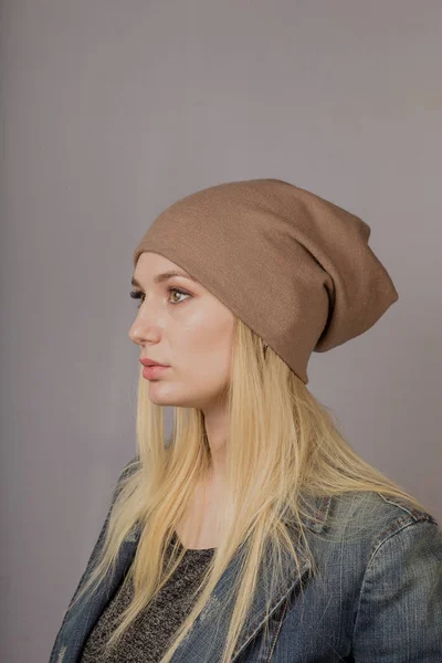 Retrato de una hermosa joven en un elegante tocado con maquillaje natural sobre un fondo gris . — Foto de Stock