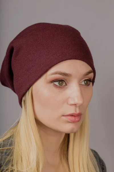 Retrato de una hermosa joven en un elegante tocado con maquillaje natural sobre un fondo gris . —  Fotos de Stock