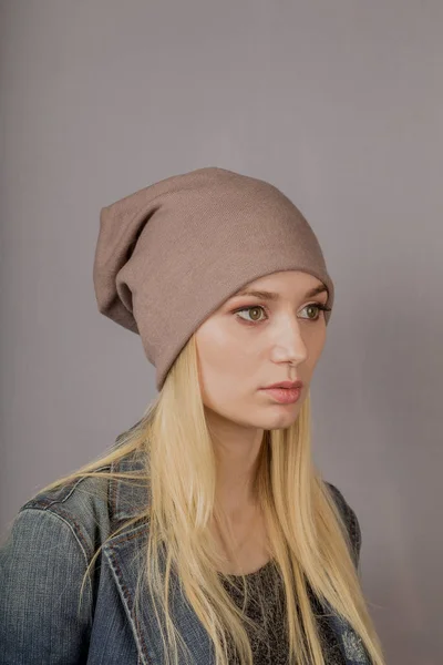 Retrato de una hermosa joven en un elegante tocado con maquillaje natural sobre un fondo gris . —  Fotos de Stock