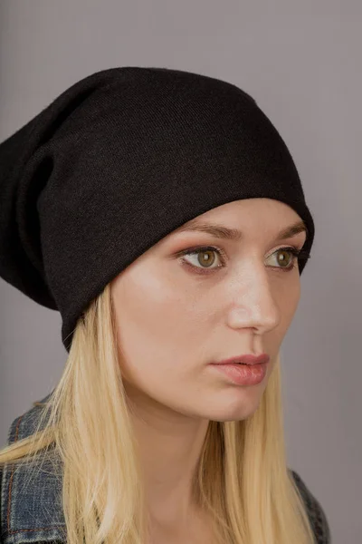 Portrait of a beautiful young girl in a stylish headdress with natural makeup on a gray background. — Stock Photo, Image