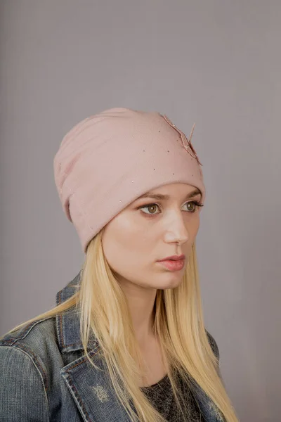 Retrato de una hermosa joven en un elegante tocado con maquillaje natural sobre un fondo gris . —  Fotos de Stock