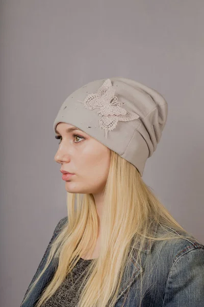 Retrato de una hermosa joven en un elegante tocado con maquillaje natural sobre un fondo gris . — Foto de Stock