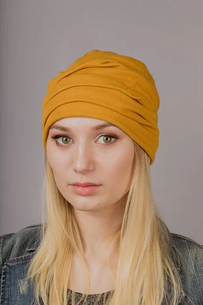 Portrait of a beautiful young girl in a stylish headdress with natural makeup on a gray background. — Stock Photo, Image