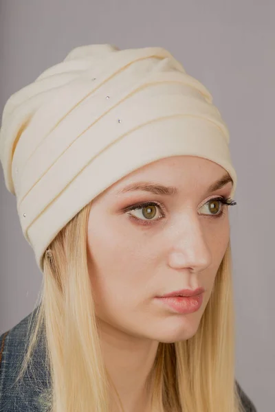 Portrait of a beautiful young girl in a stylish headdress with natural makeup on a gray background. — Stock Photo, Image
