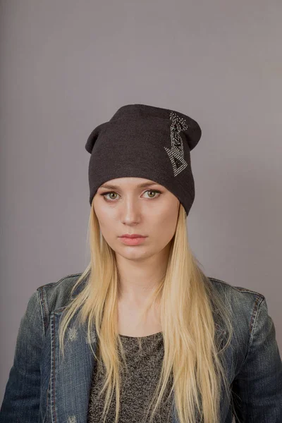 Porträt eines schönen jungen Mädchens in einem stilvollen Kopfschmuck mit natürlichem Make-up auf grauem Hintergrund. — Stockfoto