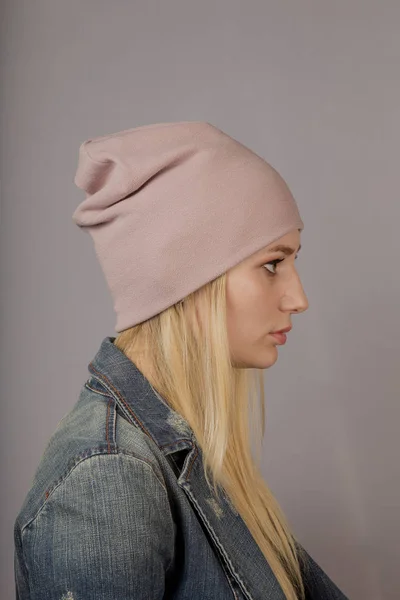 Portret van een mooi jong meisje in een stijlvolle hoofdtooi met natuurlijke make-up op een grijze achtergrond. — Stockfoto