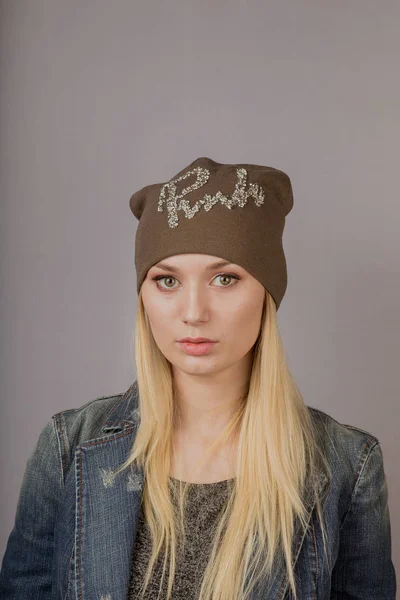 Retrato de una hermosa joven en un elegante tocado con maquillaje natural sobre un fondo gris . —  Fotos de Stock