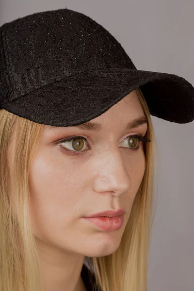 Retrato de una hermosa joven en un elegante tocado con maquillaje natural sobre un fondo gris . —  Fotos de Stock