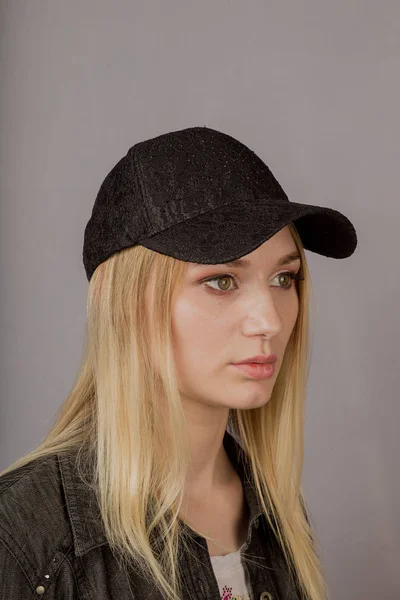 Retrato de uma bela jovem em uma cobertura para a cabeça elegante com maquiagem natural em um fundo cinza . — Fotografia de Stock