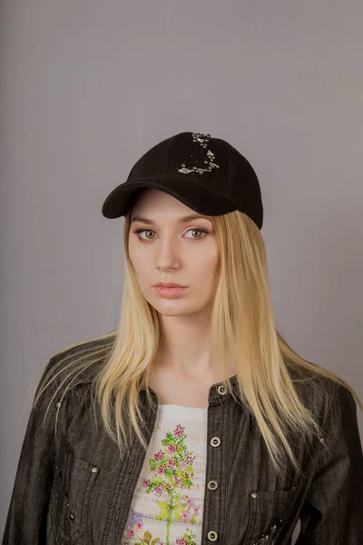 Portrait of a beautiful young girl in a stylish headdress with natural makeup on a gray background. — Stock Photo, Image