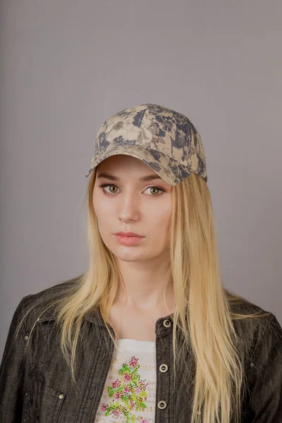 Retrato de uma bela jovem em uma cobertura para a cabeça elegante com maquiagem natural em um fundo cinza . — Fotografia de Stock