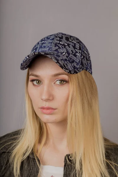 Retrato de uma bela jovem em uma cobertura para a cabeça elegante com maquiagem natural em um fundo cinza . — Fotografia de Stock