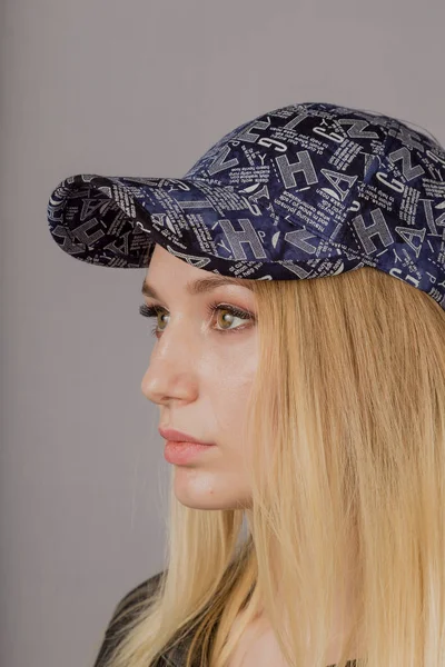 Retrato de una hermosa joven en un elegante tocado con maquillaje natural sobre un fondo gris . — Foto de Stock