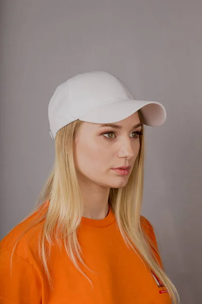 Retrato de una hermosa joven en un elegante tocado con maquillaje natural sobre un fondo gris . — Foto de Stock