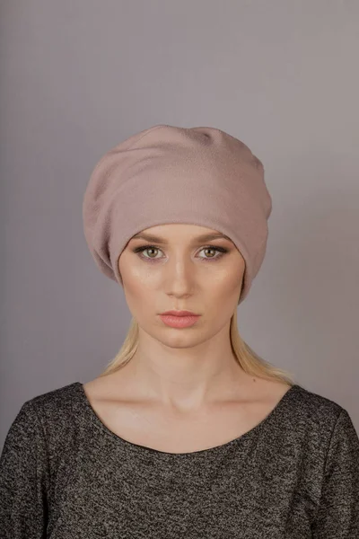 Beautiful girl with natural make-up in a headdress on a gray background. — Stock Photo, Image